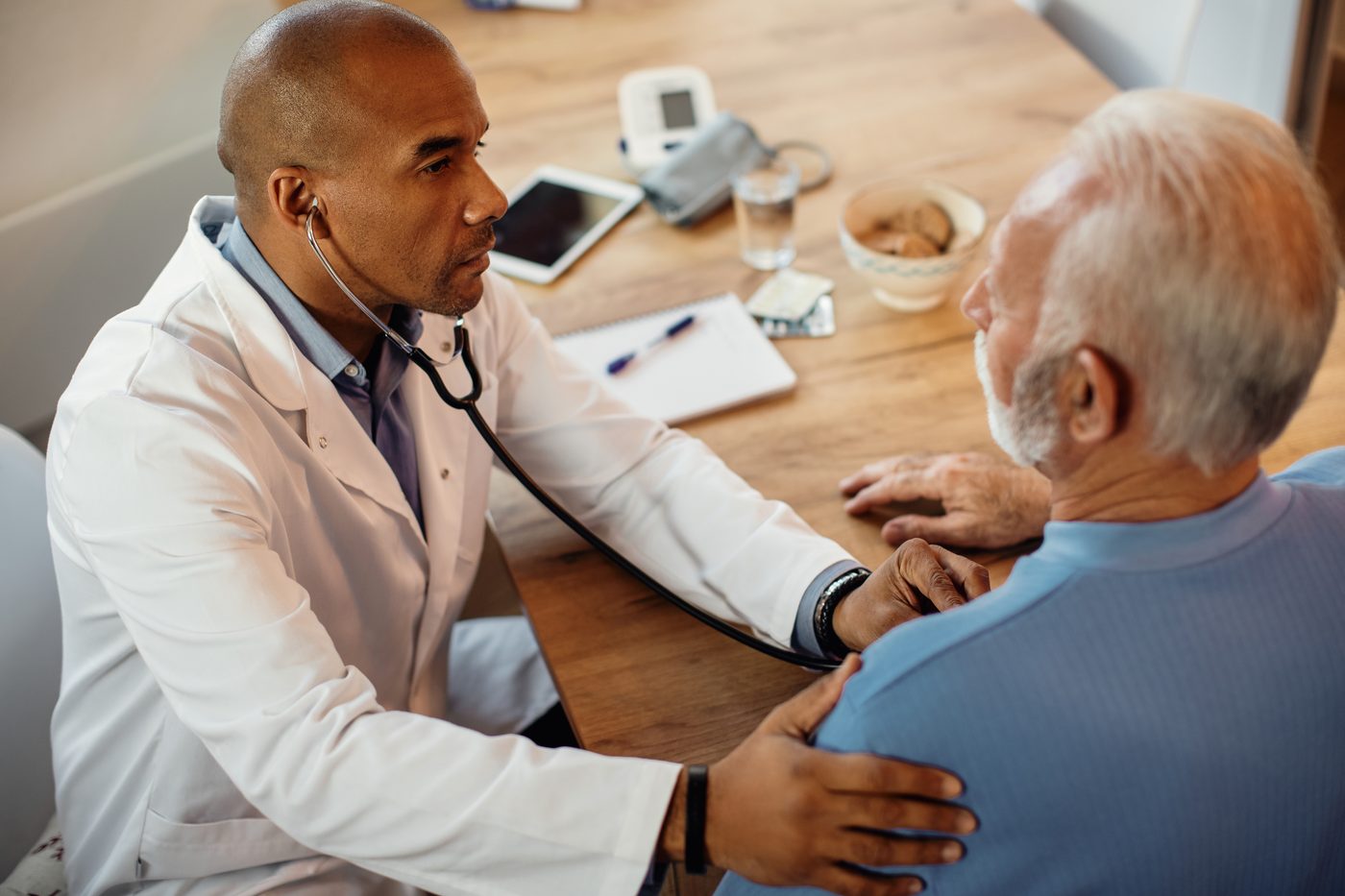 Cardiologista ausculta paciente em consulta