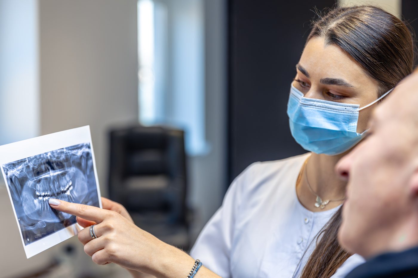Cirurgiã bucomaxilofacial mostra radiografia da face ao paciente
