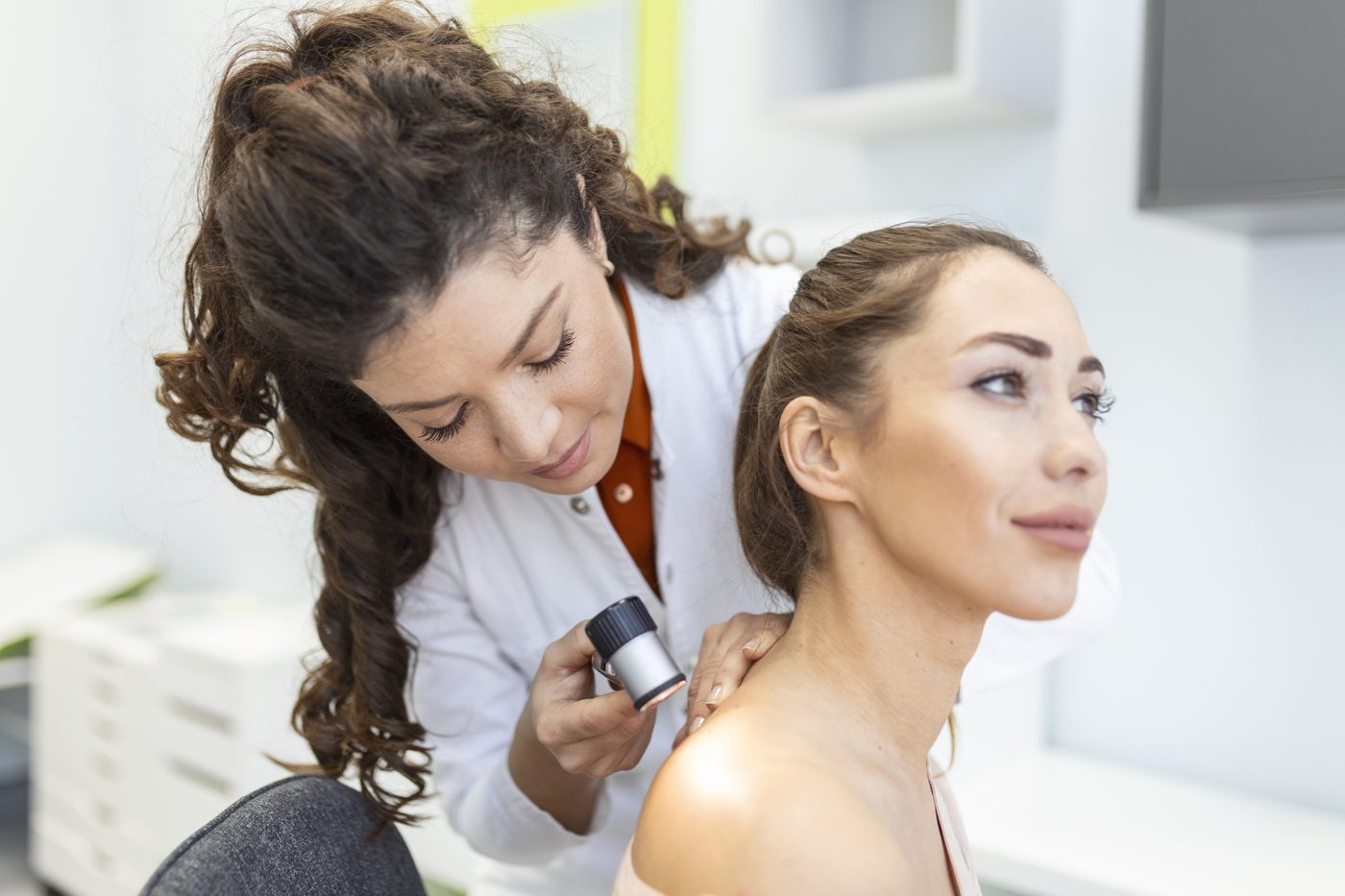 Dermatologista examina a pele de paciente com dermatoscópio